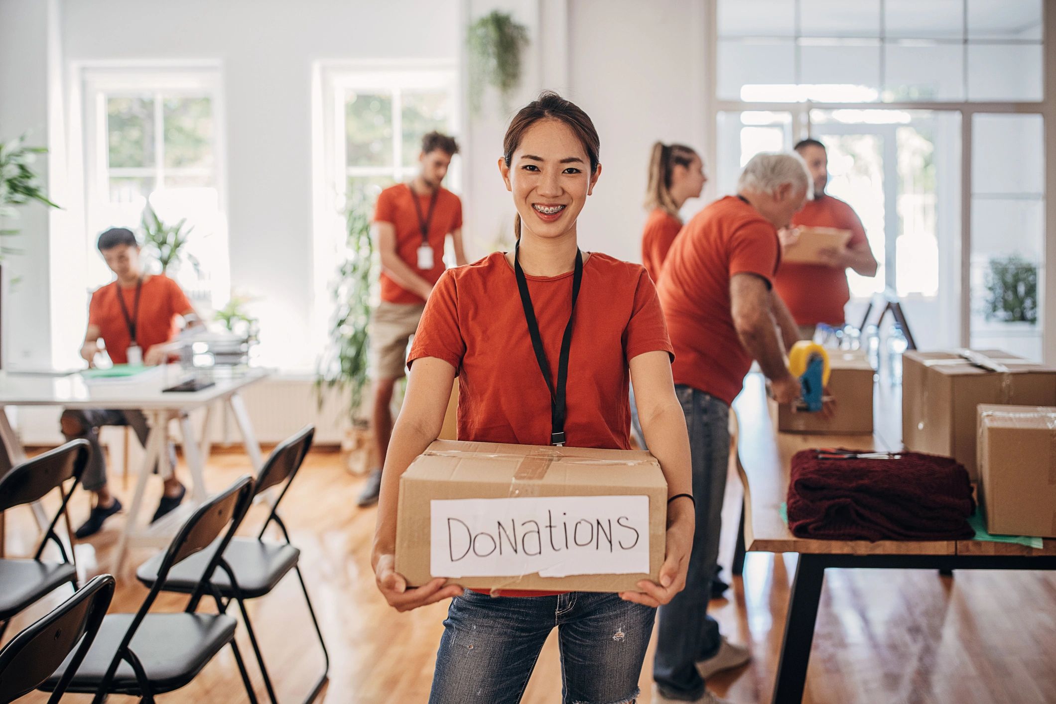 Volunteer holding a donations box with smiling team in background.