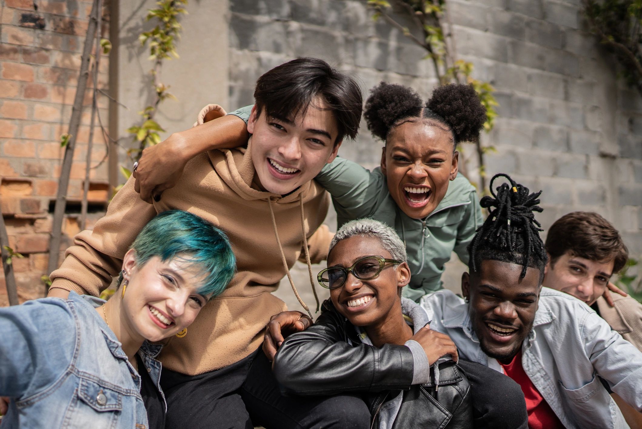 A joyful group of diverse friends posing together outdoors.