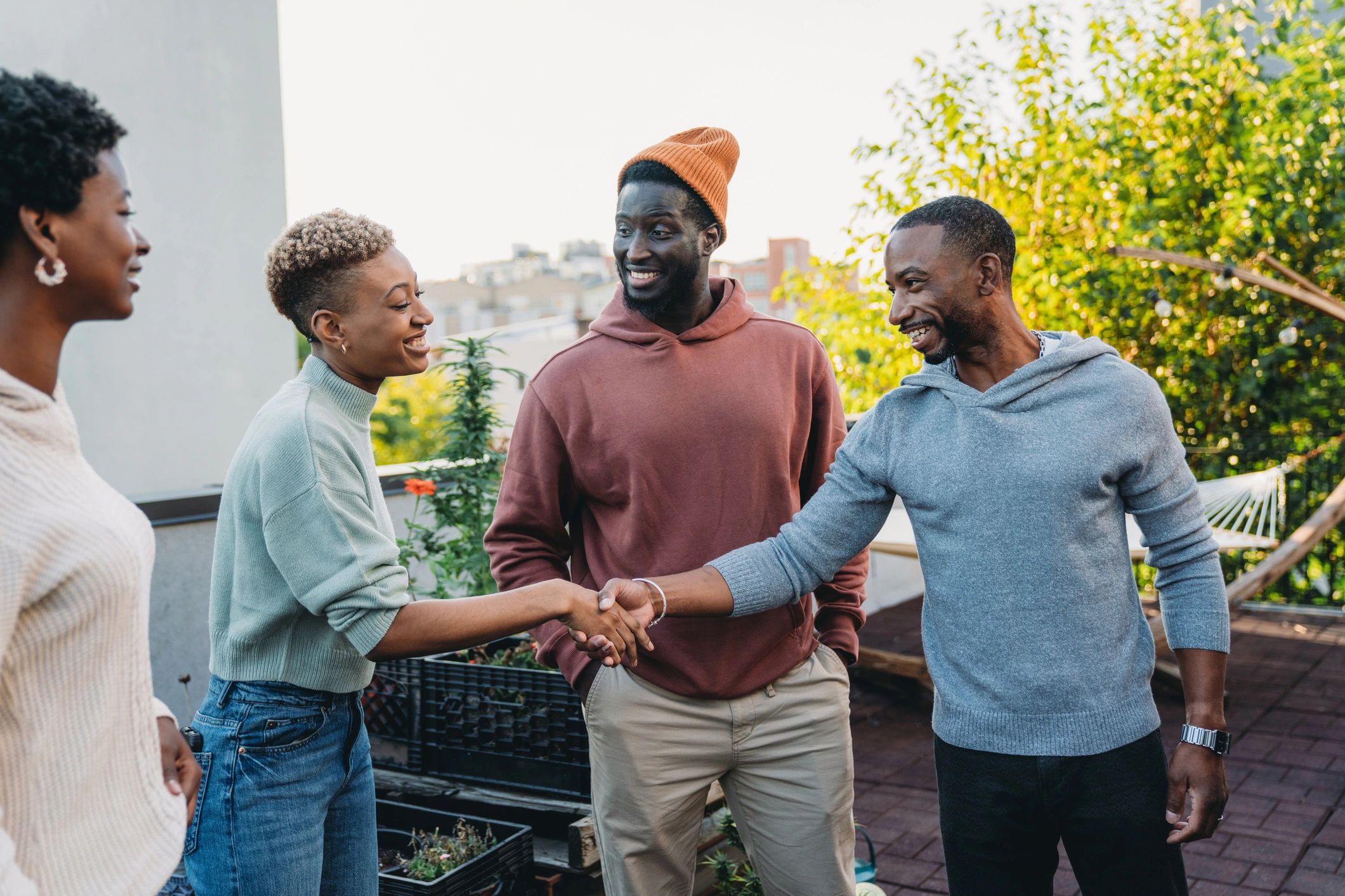 Three men joyfully greeting each other outdoors with a handshake.