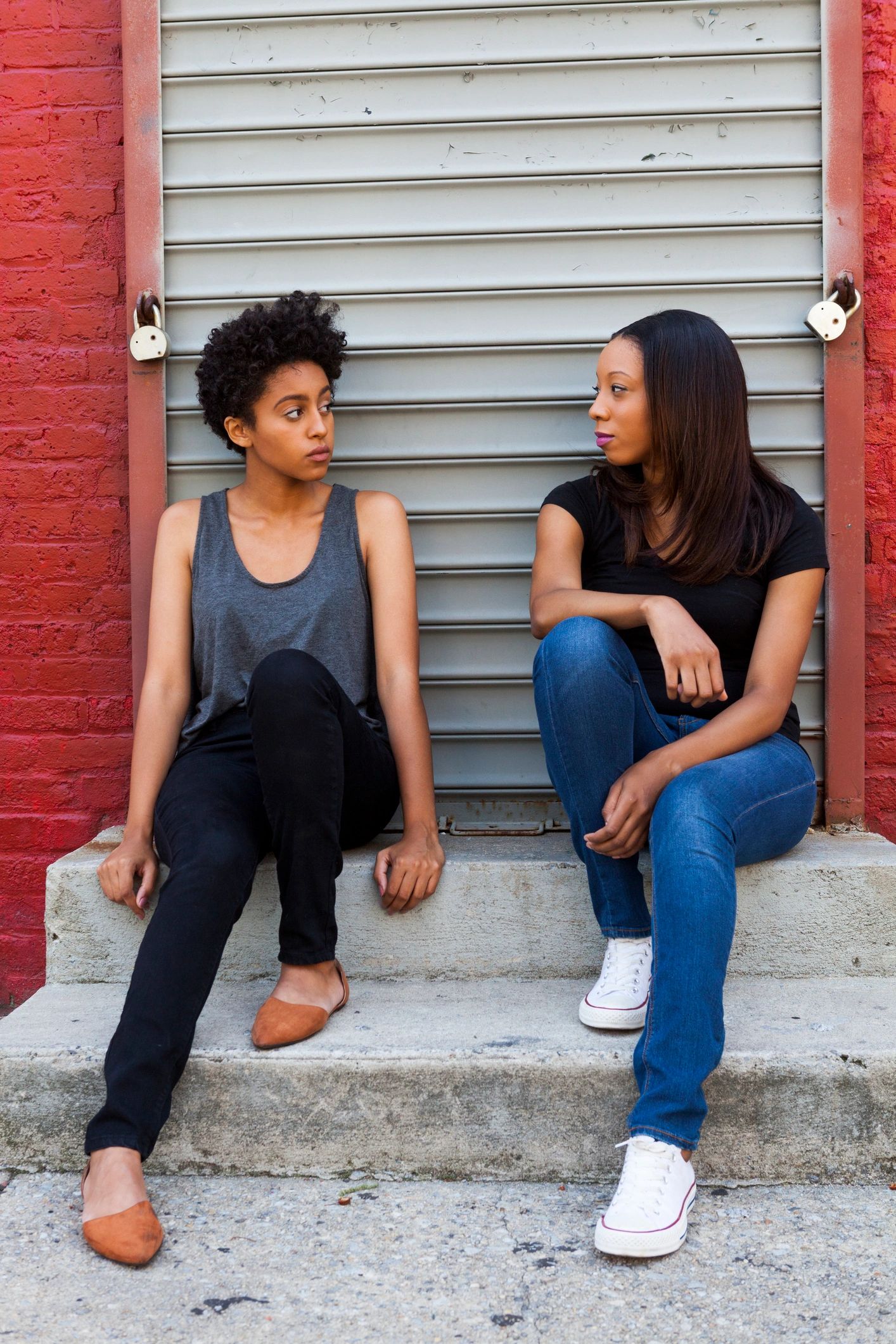 Two women sitting on steps, engaged in conversation.