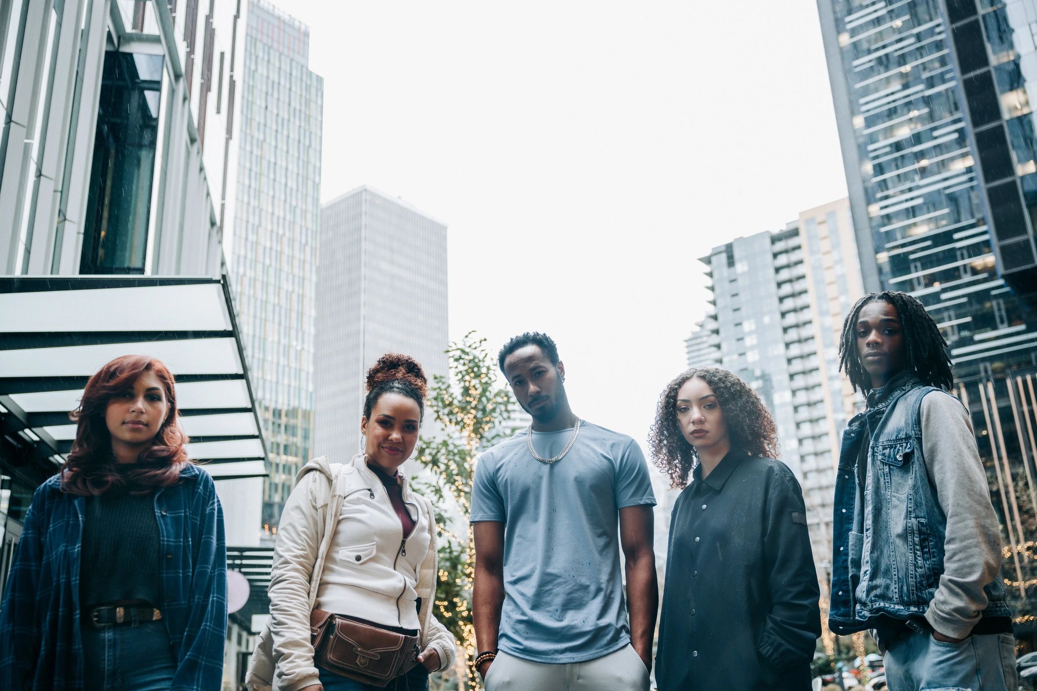 Three diverse friends standing together outdoors in an urban setting.