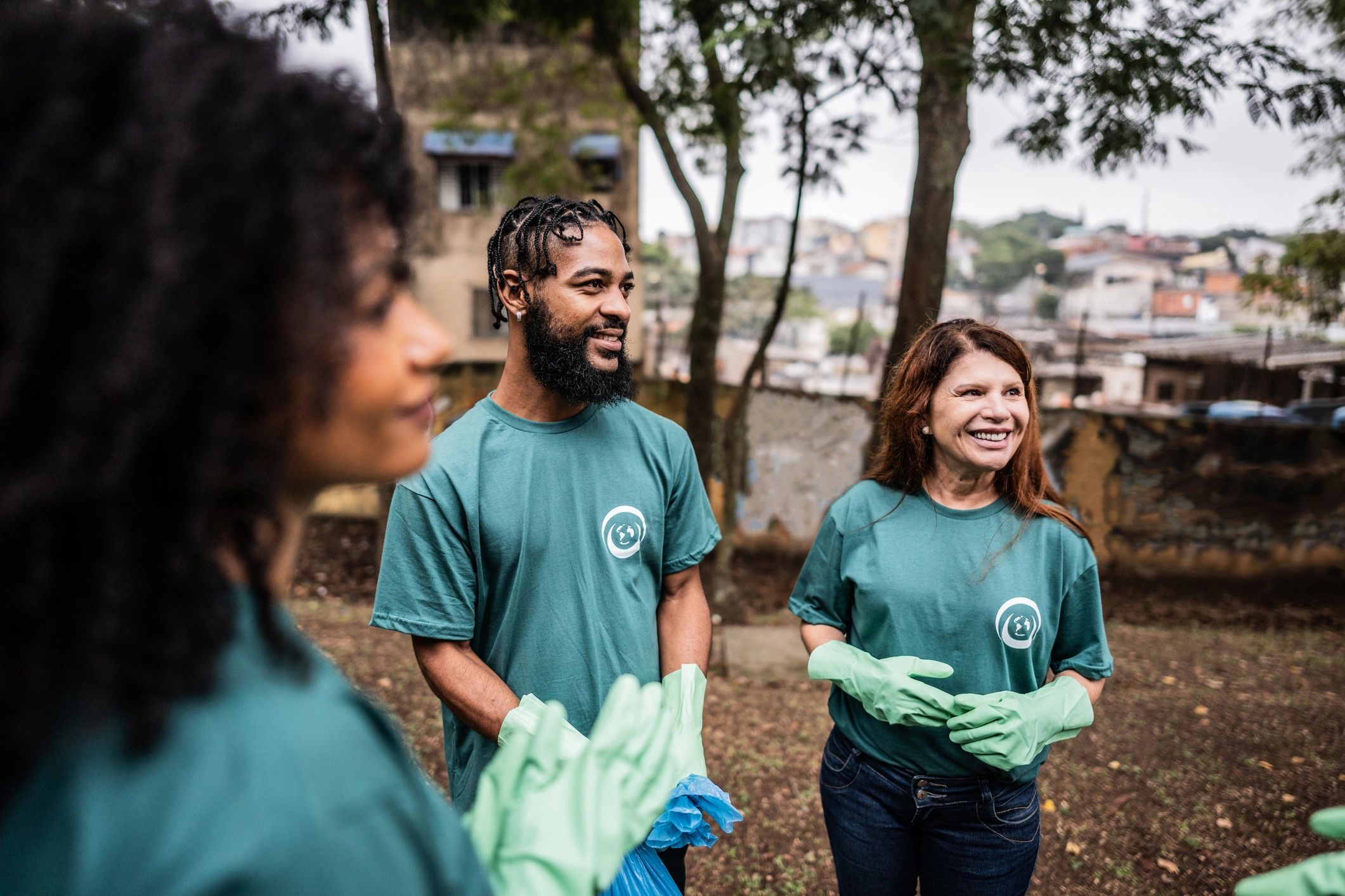 Three people volunteering outdoors, smiling and ready to clean.