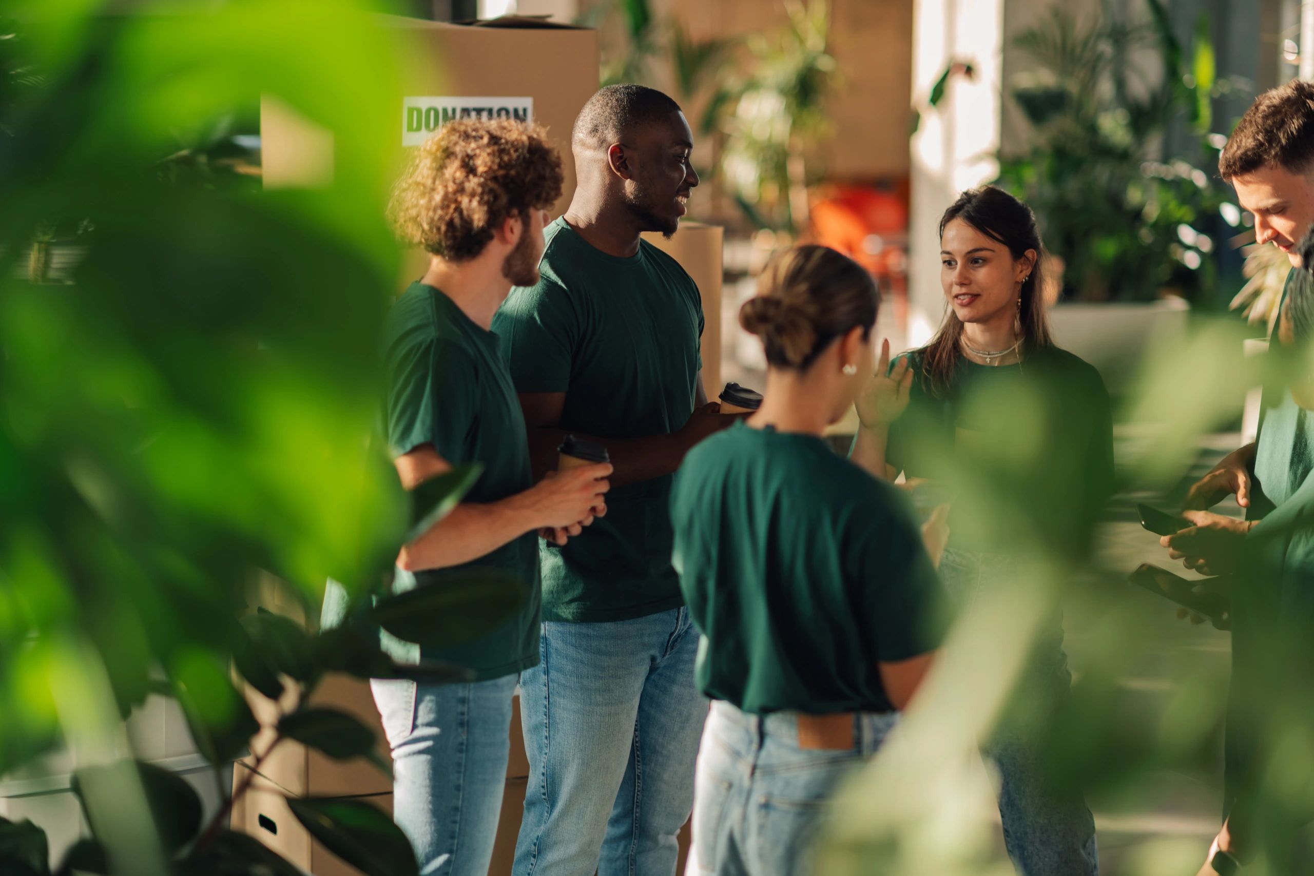 Diverse people chatting and enjoying coffee in a bright indoor garden setting.