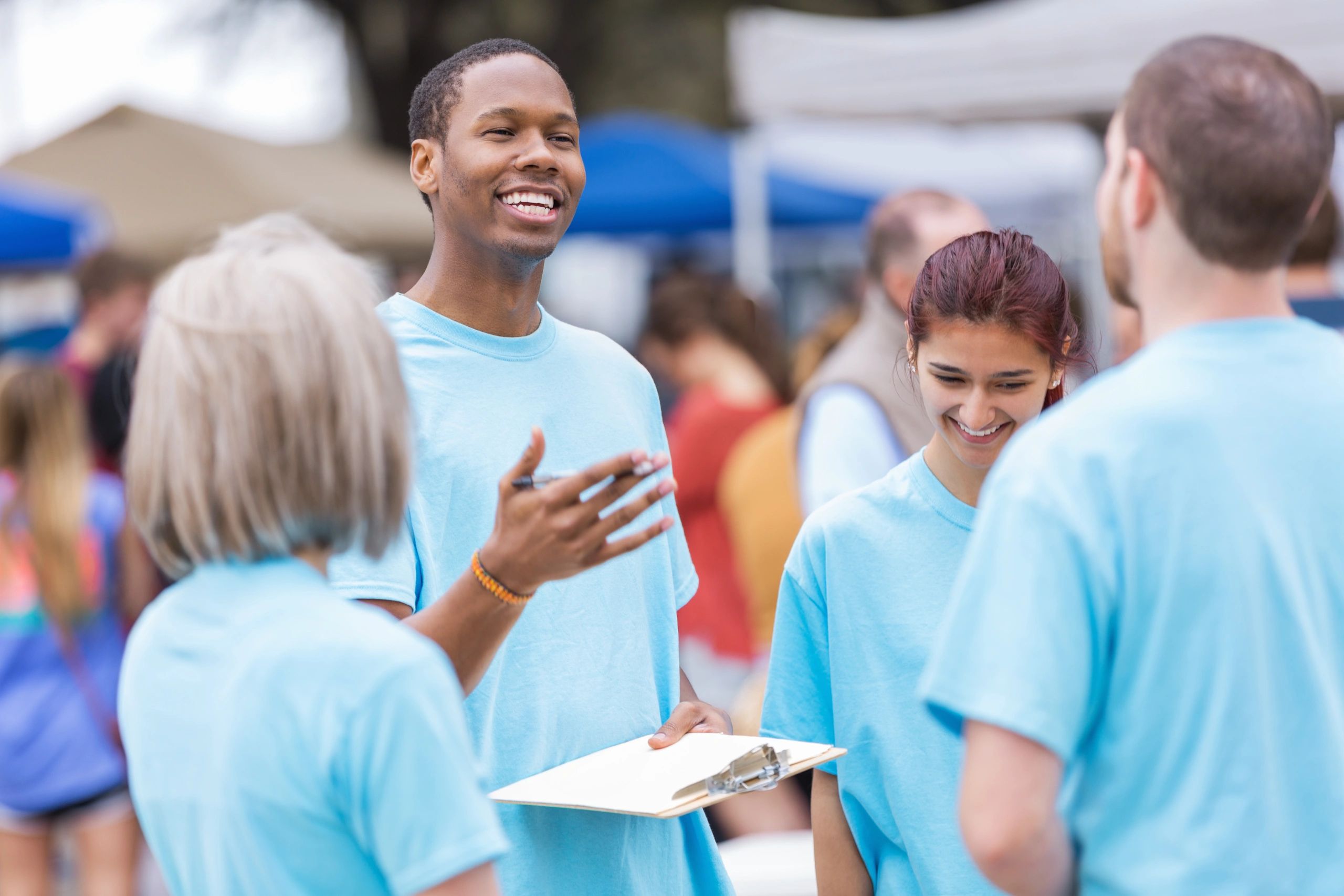 Volunteers in blue shirts engaging in friendly conversation outdoors.