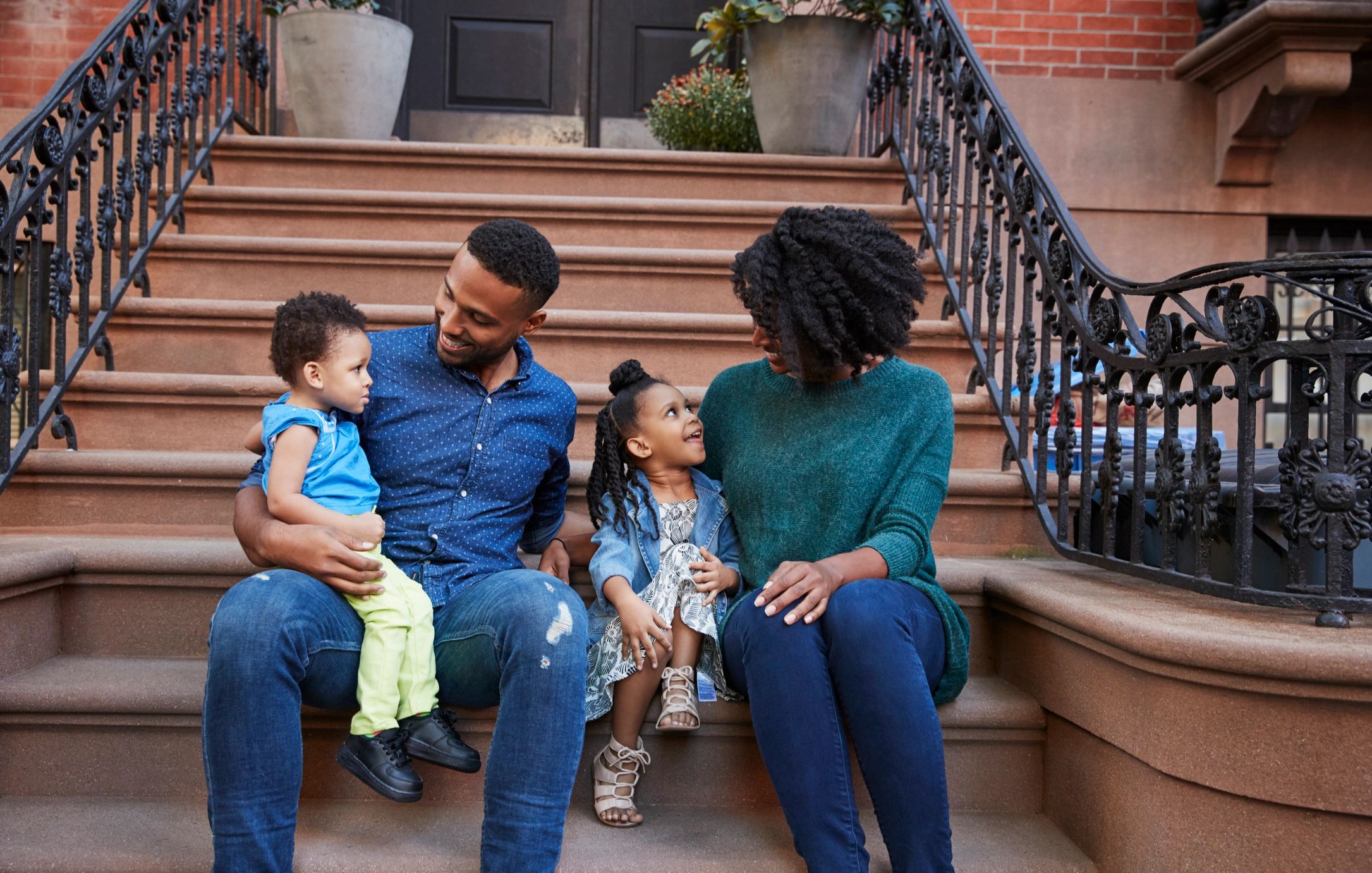 Happy family sitting on outdoor steps, enjoying quality time together.